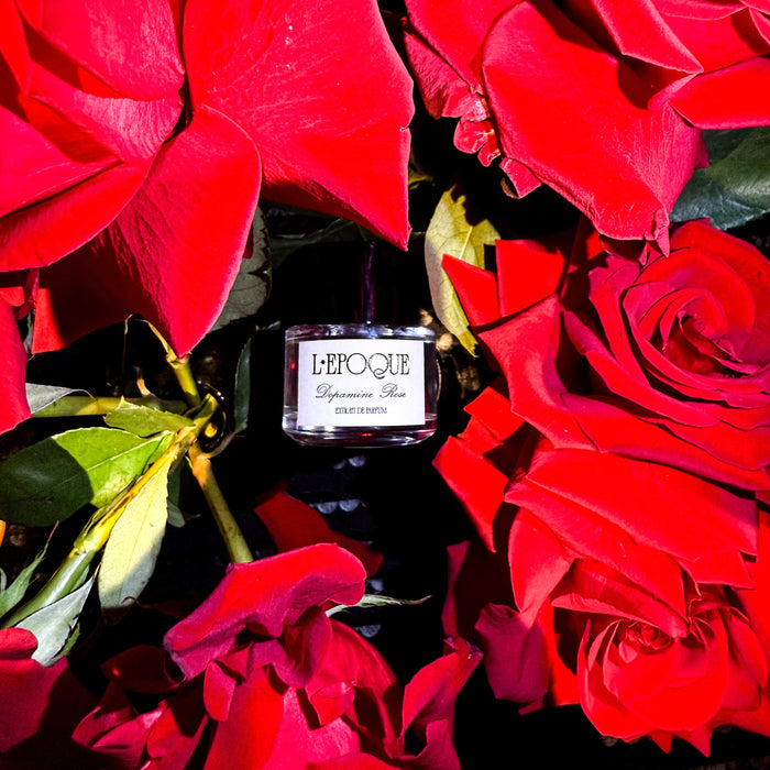 L'epoque Parfums Dopamine Rose Fragrance bottle surrounded by red roses 