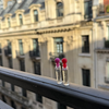 Two small l'epoque parfums sample bottles with colorful caps and googly eyes on a balcony railing in paris