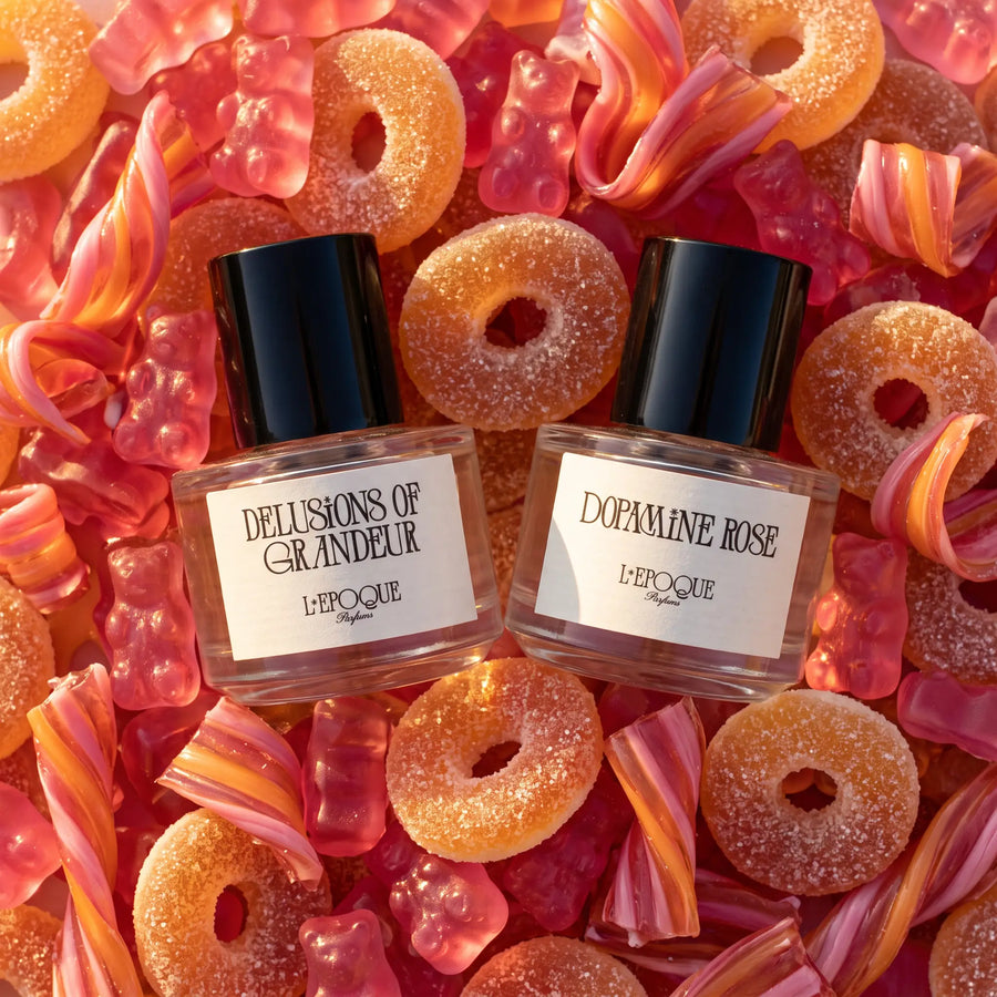 L'Epoque Parfums Dopamine Dose duo — Delusions of Grandeur and Dopamine Rose bottles on pink and orange gummy candy