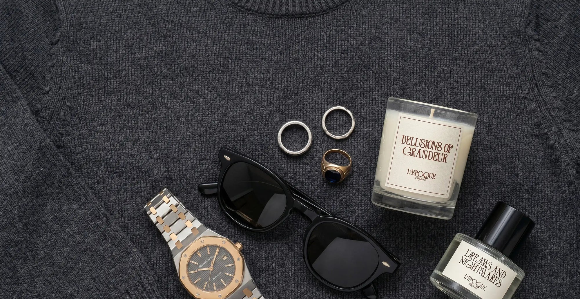 Delusions of Grandeur mini candle and Dreams and Nightmares EDP by L'Epoque Parfums styled with a luxury watch, sunglasses, and rings for Father's Day
