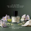 Inner Child eau de parfum by L'Epoque surrounded by lavender freesia, lily of the valley, a lime slice, and folded linen on a sage green background