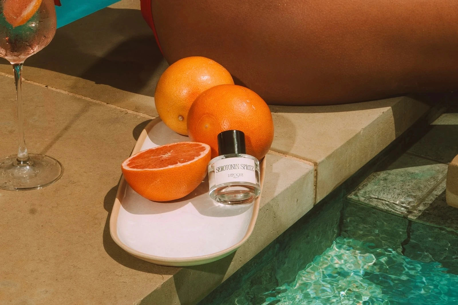 Inner Child eau de parfum 30mL by L'Epoque, held to the neck of a model wearing a white robe and gold jewelry