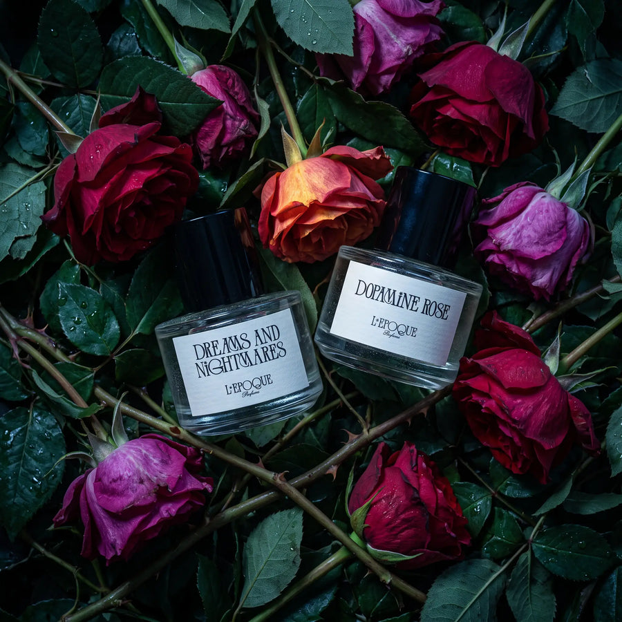L'Epoque Parfums The Haunted Rose Garden duo — Dreams and Nightmares and Dopamine Rose bottles among dark red and purple roses